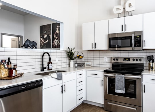 A modern kitchen with white cabinets and a black stove top.at Converge KC Uptown, Kansas City, 64111