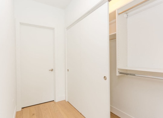 a bedroom with white walls and a closet and a door