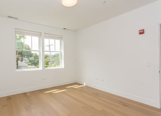 a living room with white walls and a window and wooden floors