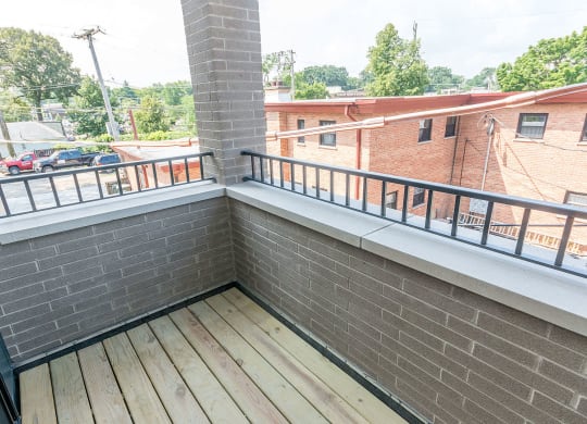 a balcony with a brick wall and a wooden floor