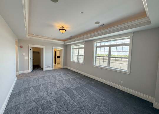 A large empty room with a patterned carpet and a window overlooking the sea.