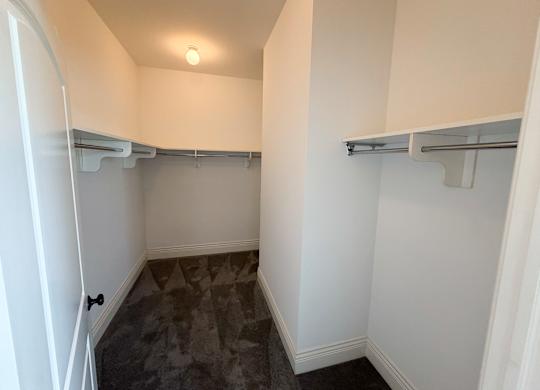 A small, empty room with a grey carpet and white walls.