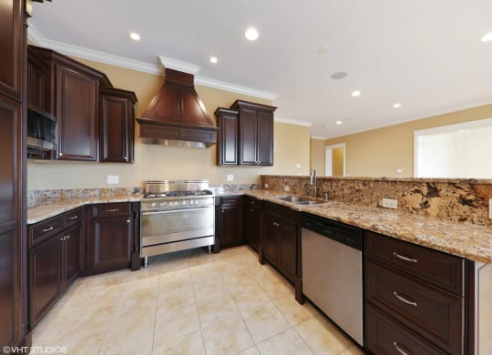 a large kitchen with granite counter tops and dark cabinets