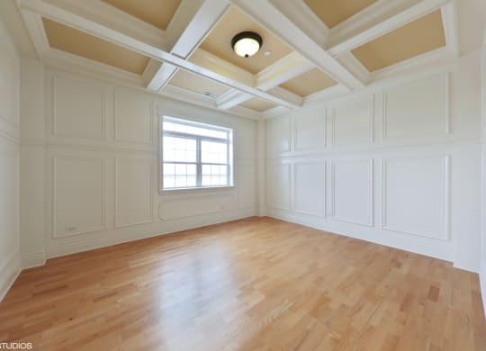 an empty living room with wood floors and white walls and a window