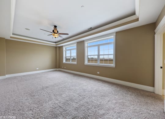 an empty living room with a ceiling fan and two windows