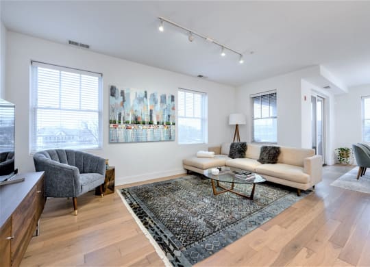a living room with a couch and two chairs and a rug