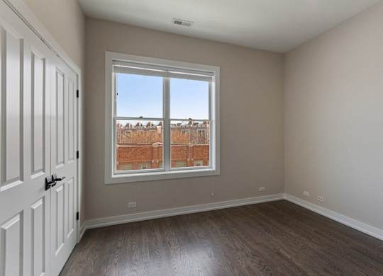 an empty living room with a window and wooden floors
