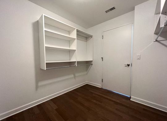 a bedroom with white walls and a closet with shelves
