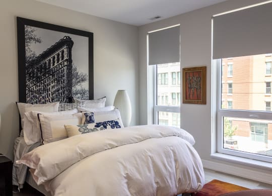 a bedroom with a bed and two windows and a painting on the wall