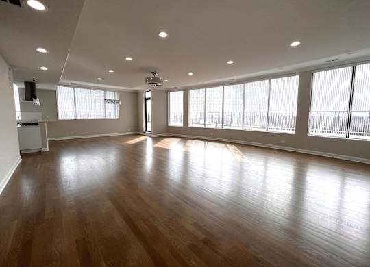 an empty living room with wood floors and large windows