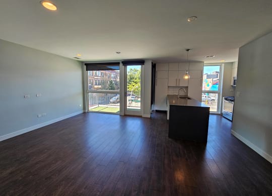 an empty living room with a kitchen and sliding glass doors