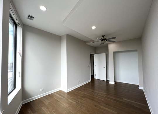 a living room with white walls and a ceiling fan