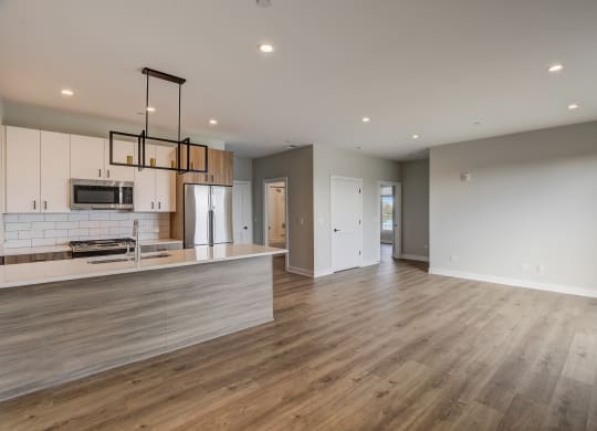 an open kitchen and living room with white cabinets and wood floors