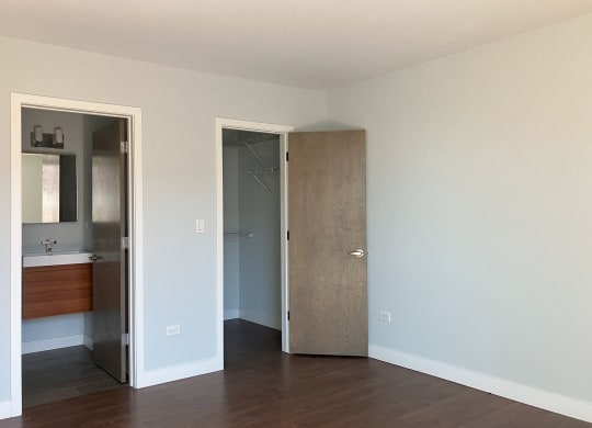 an empty room with a door to a bathroom and a mirror