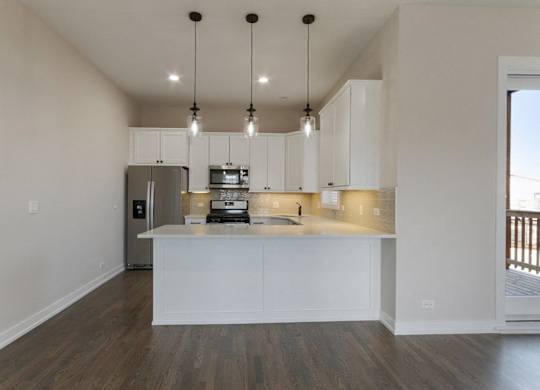a kitchen with white cabinets and a counter top and a refrigerator