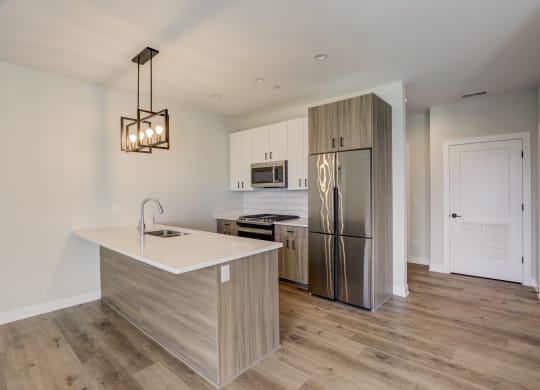 a kitchen with a large island and stainless steel refrigerator