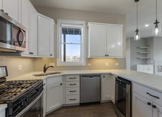 a kitchen with white cabinets and a stove and a window