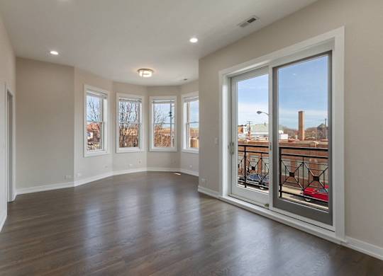 an empty living room with large windows and a wood floor