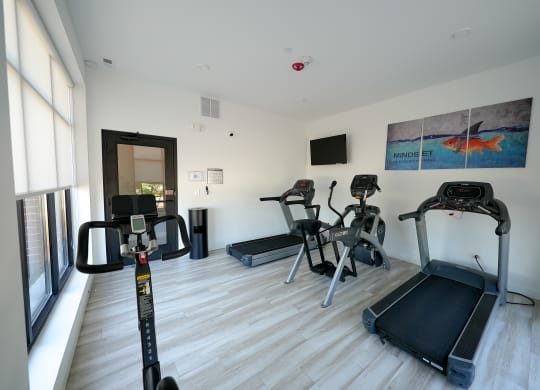 a gym with various exercise equipment on the floor and a window