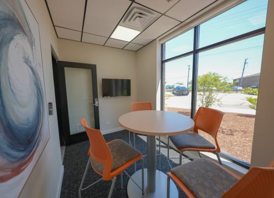a room with a table and chairs in front of a window