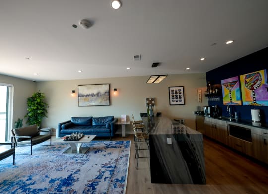 a living room with a kitchen and a blue rug