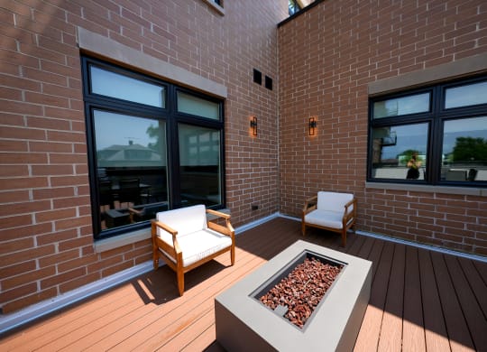 a covered patio with two chairs and a fire pit