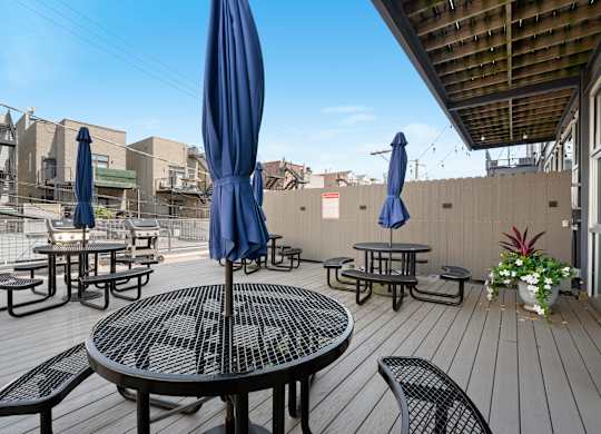A patio with tables and chairs and umbrellas.
