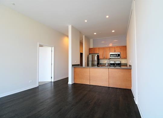a living room with wood flooring and a kitchen