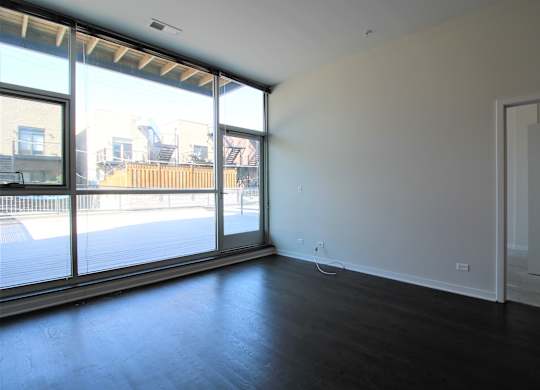 an empty living room with a large window and wood flooring