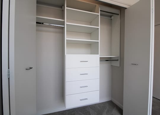 a walk in closet with white cabinets and drawers