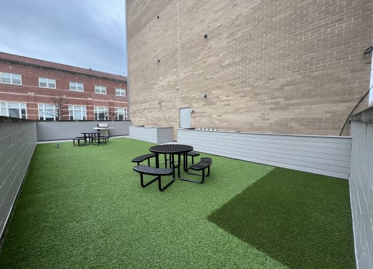 a roof deck with a table and chairs on a green lawn
