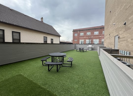 a rooftop patio with a green lawn and tables