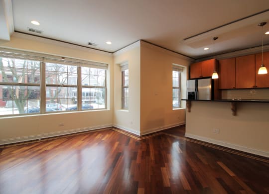 an empty living room with a large window and wood floors