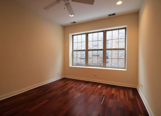 an empty living room with a large window and wooden floors
