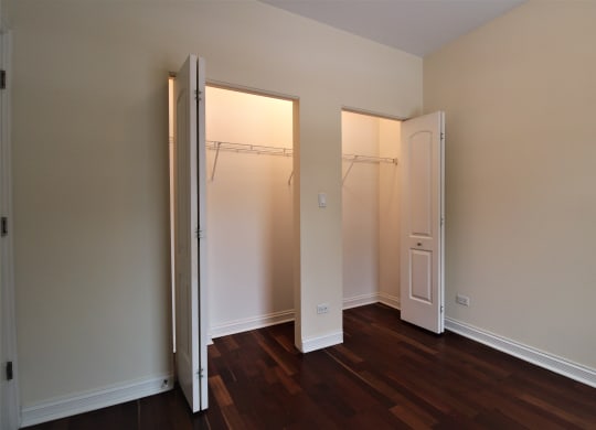 a bedroom with two closet doors and a hard wood floor