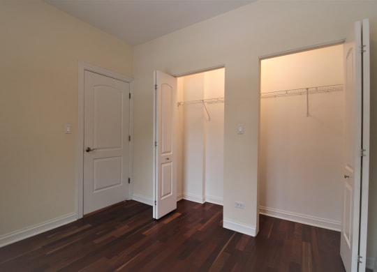 a bedroom with two closets and a wood floor and white doors