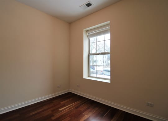 an empty room with a window and wooden floors