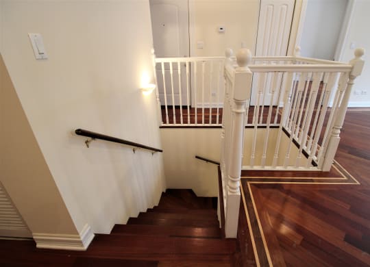 a stairwell in a home with wooden floors and a white staircase with white rails