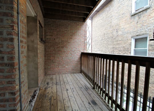 the back deck of the house has brick walls and a wooden railing