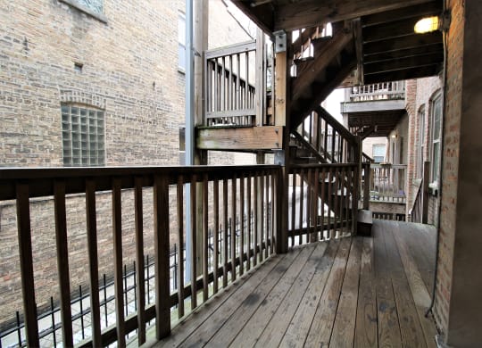 a balcony with wooden floors and stairs in a brick building