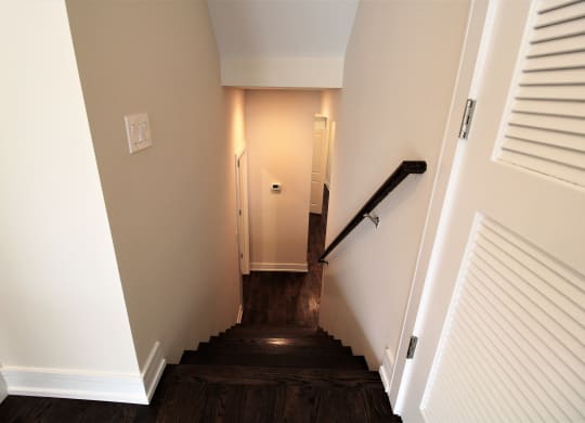 a stairwell in a home with wood floors and white walls and a white door