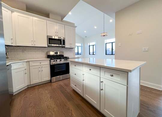 A kitchen with white cabinets and a wooden floor.