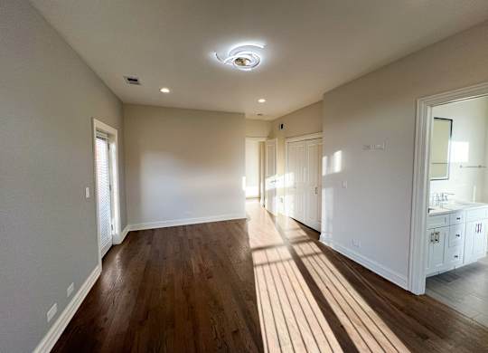 A spacious room with wooden floors and white walls.