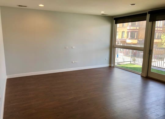 an empty living room with wood floors and a sliding glass door