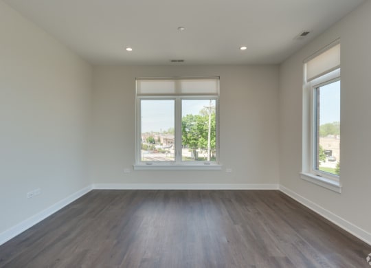 an empty living room with wood floors and a window