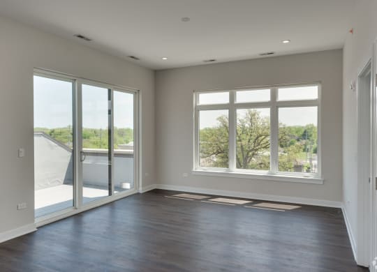 an empty living room with large windows and a balcony