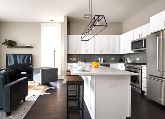 a kitchen and living room with white cabinets and stainless steel appliances