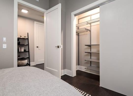 a closet in a bedroom with a white door and a white bed