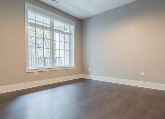an empty room with wood floors and a large window