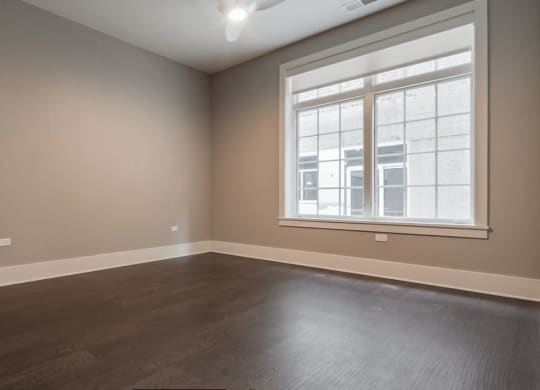 an empty living room with wood floors and a window